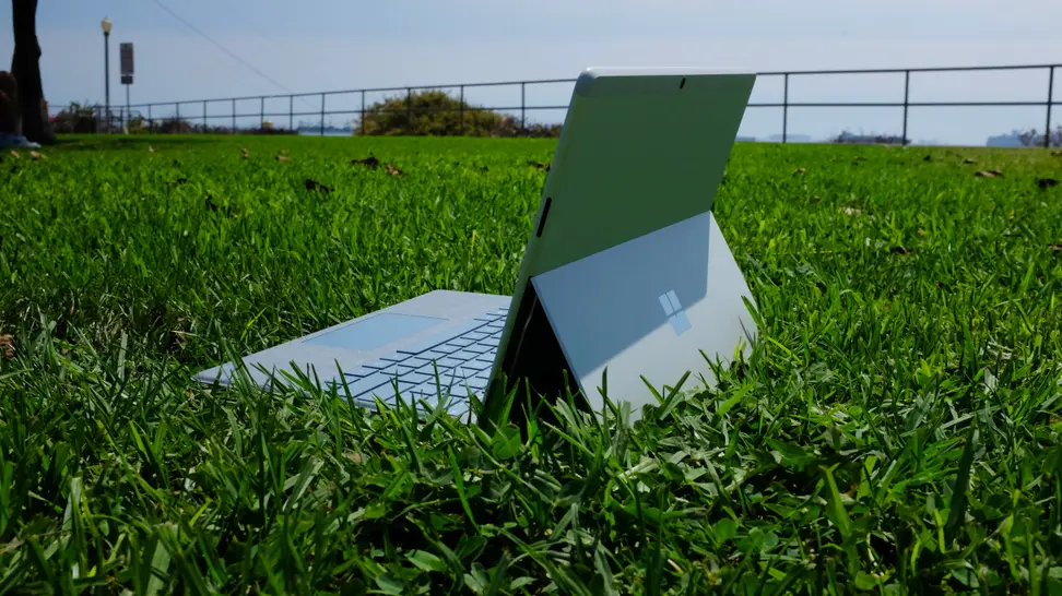 The Surface Pro X, with Type Cover keyboard attached, placed out on a field of grass.