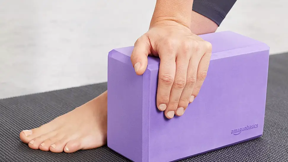 A yoga practitioner balances on a foam yoga block.