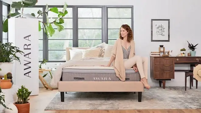 Person sitting on top of Awara mattress in bedroom.