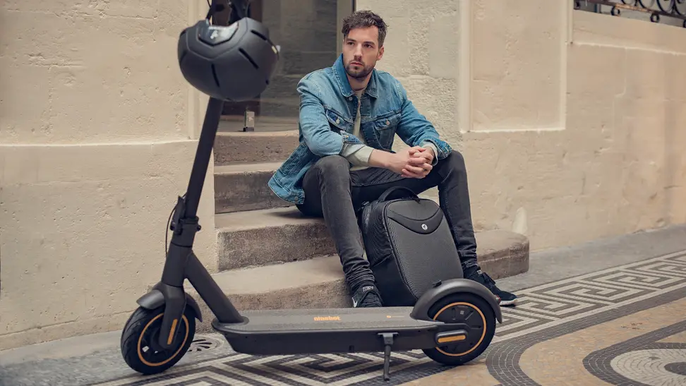 A young model sits on concrete steps beside a Segway electric scooter.