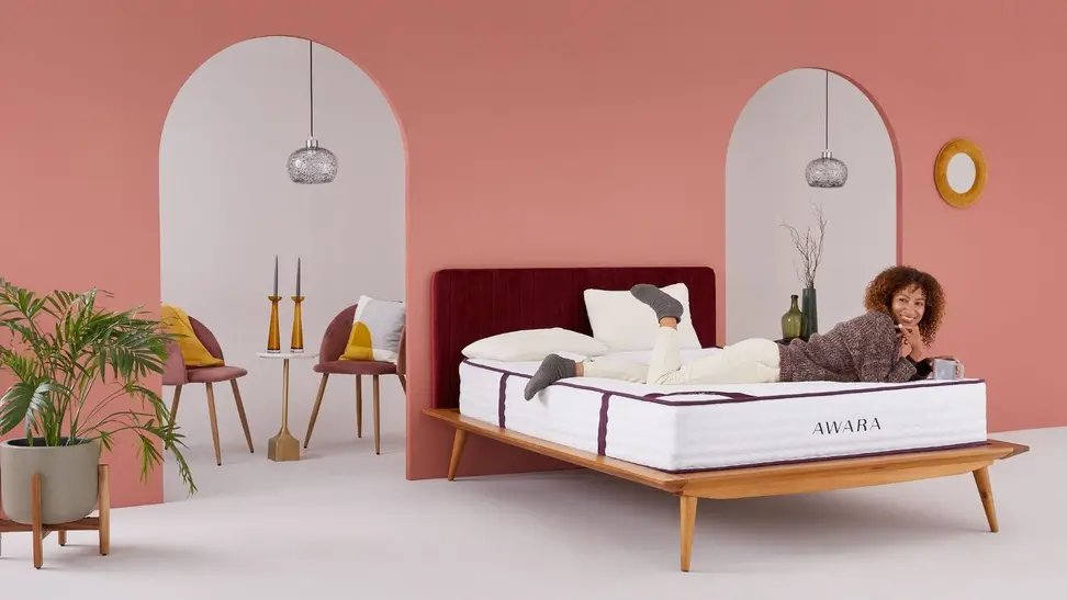 A person lays on a bed inside a pink room.