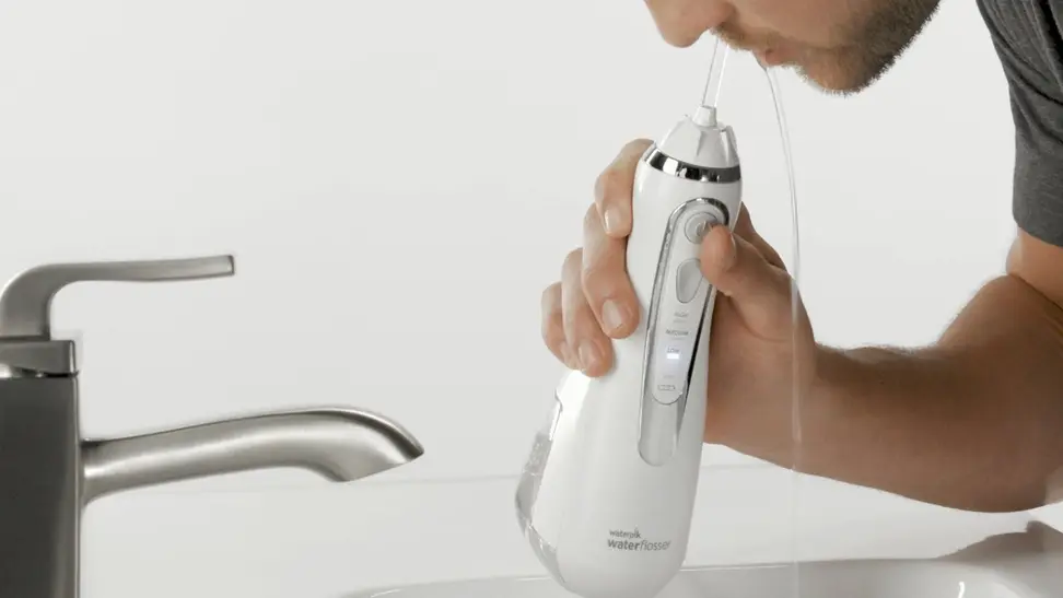 Close-up of a model using a Waterpik water flosser.