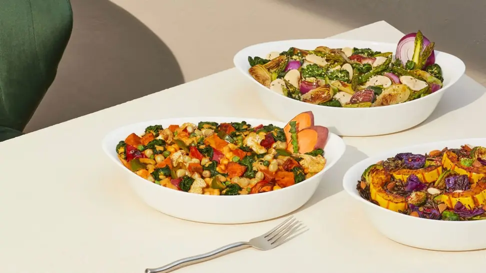 On left, raw veggies and other ingredients placed in Harvest Bakes-sized bowl. On right, hand digging into ready-to-eat Harvest Bakes with a fork, toaster oven in background.