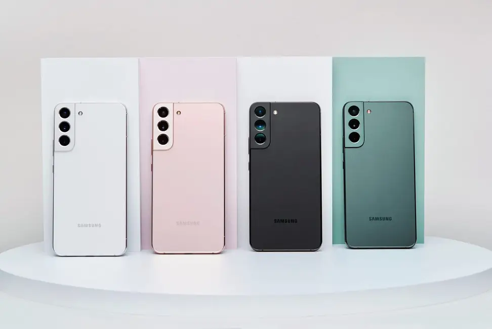 Four Samsung Galaxy S22 smartphones lined up in a row. They are white, rose gold, black, and mint green.