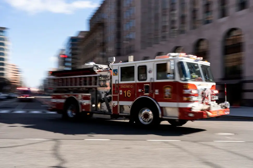 Photo of a fast-moving red-and-white firetruck.