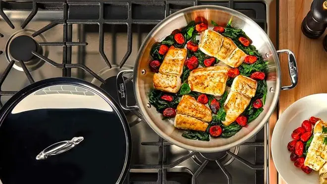 two pots on stove, one open with chicken and vegetables cooking