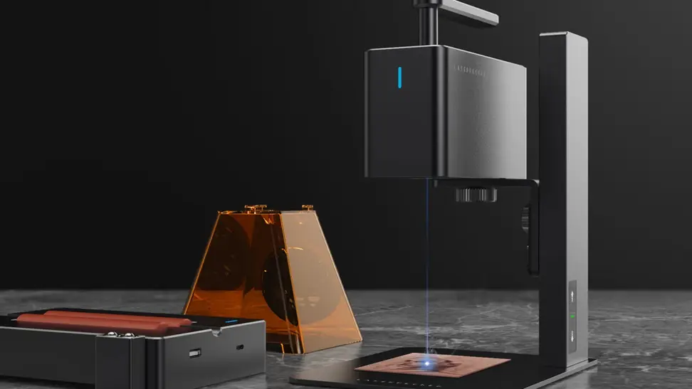 Photo of a laser engraver machine in use, a beam of focused blue light emitting from the underside.
