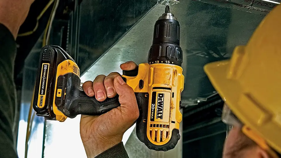 Photo of a person in a yellow helmet and safety glasses using a DeWalt drill.