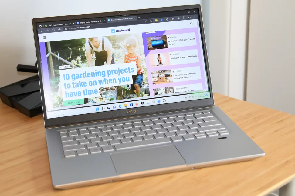 An open and powered-on laptop sitting on top of. light brown wooden surface