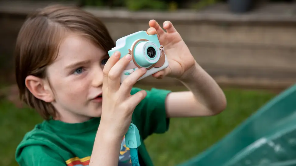 A young child happily takes a photo with their Kidamento kids digital camera