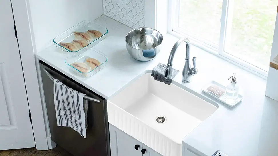 A farm sink placed in a lovely white-interior kitchen.