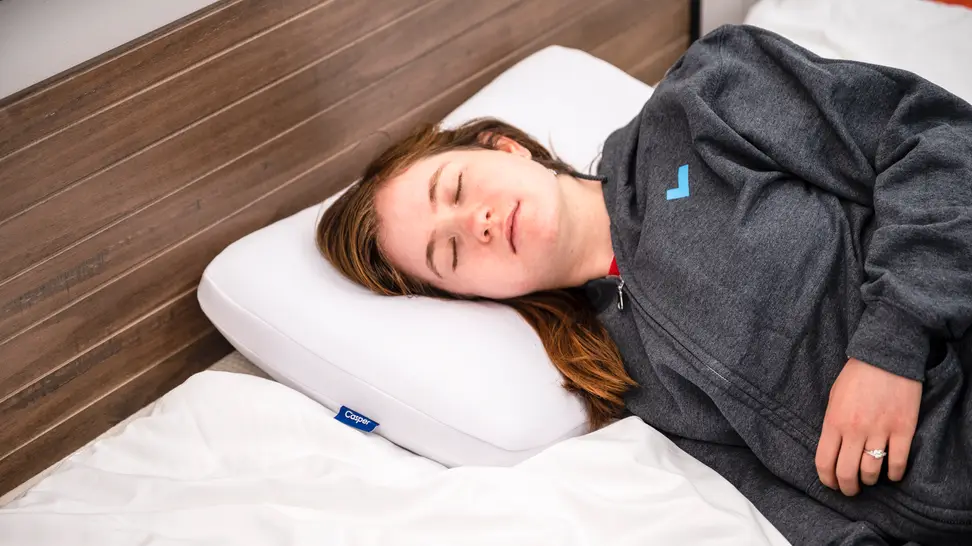 Person laying in bed with eyes closed on memory foam pillow.