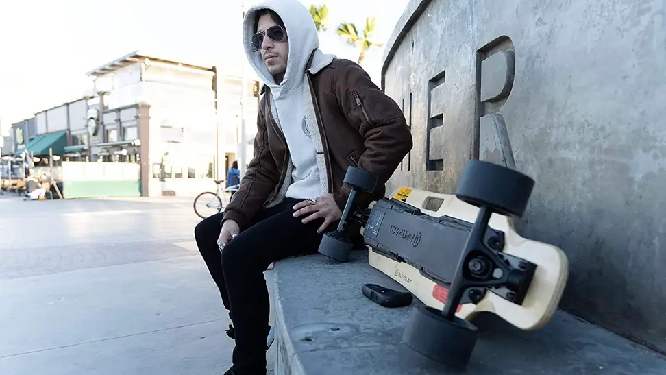A longboard rider taking a quick break from riding his electric longboard.