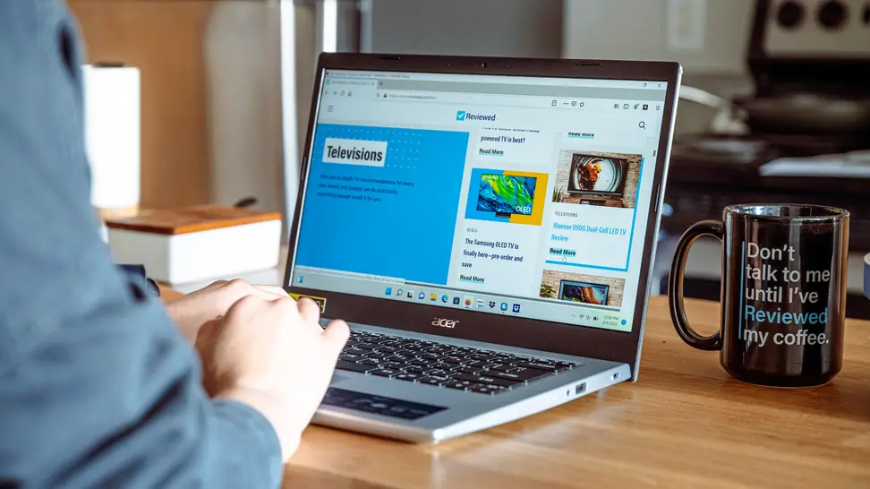 Person uses a laptop on a wooden desk