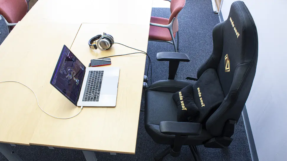 The AndaSeat Phantom 3 gaming chair placed in front of an office desk with a laptop and a pair of headphones.