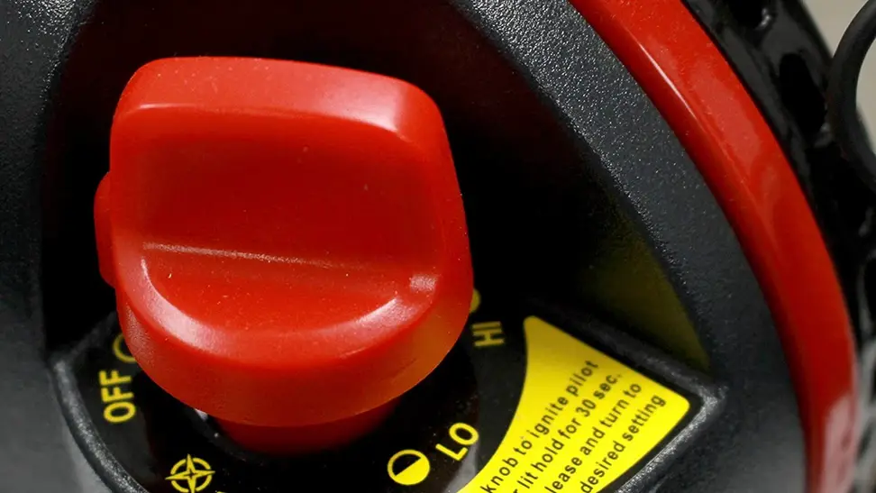 Close-up on a garage heater, operated by a large red knob.