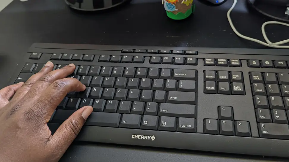 A person's hand touching a black keyboard