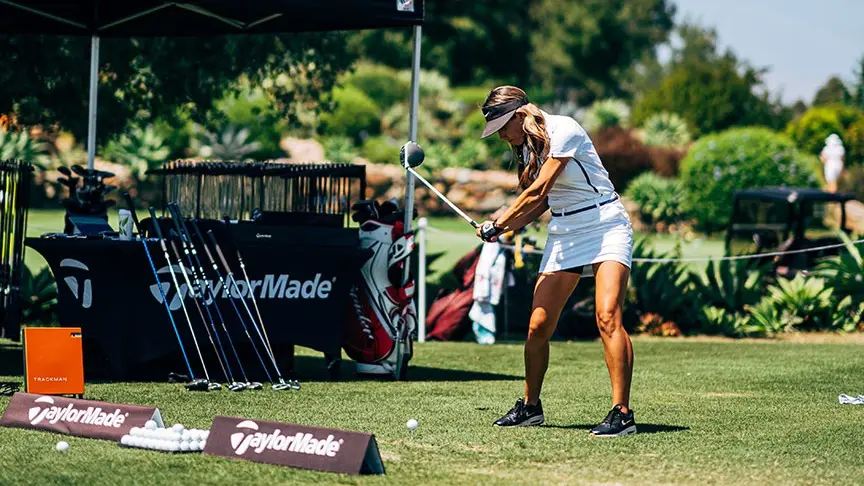 A man using his golf clubs to golf at a local resort on his day off of work.