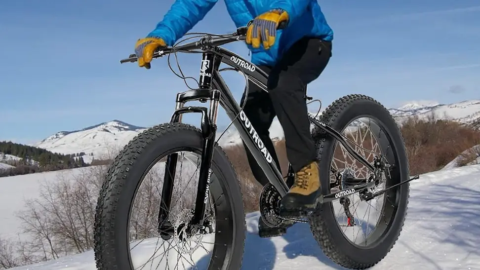 A guy riding his fat bike through snow.