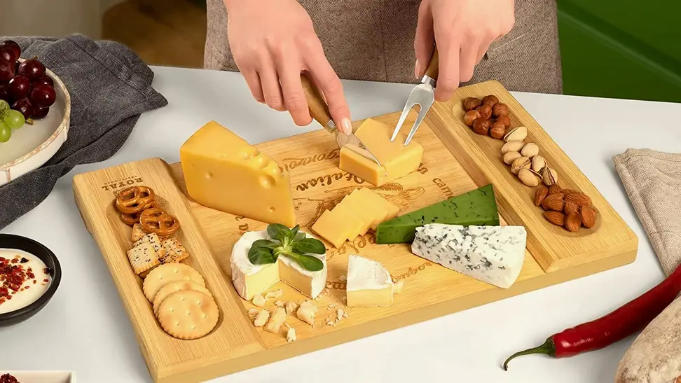 A hand model serves cheese and crackers on a Royal Craft charcuterie board.