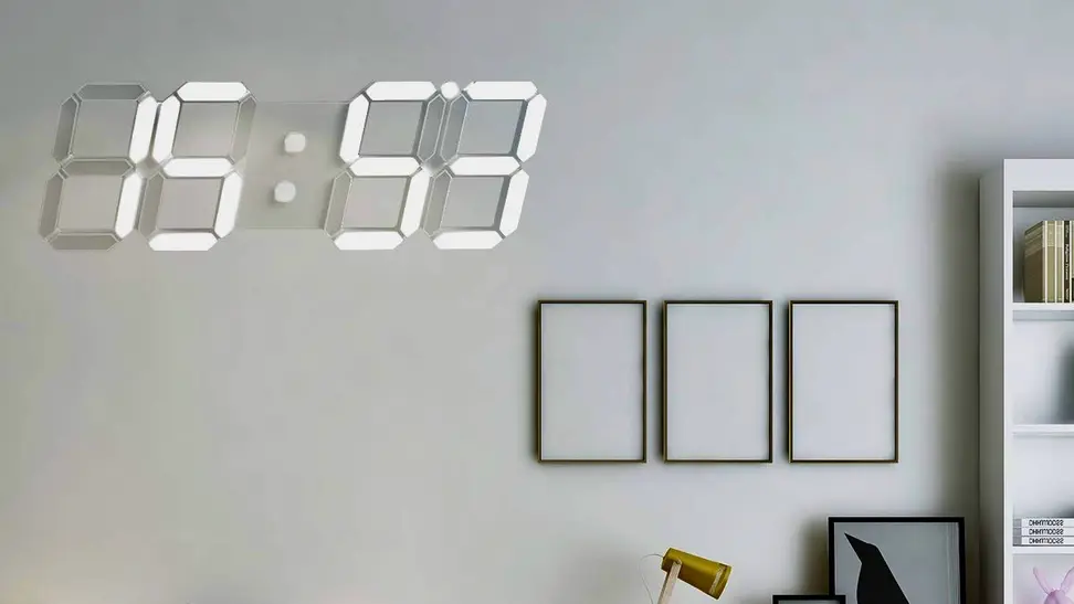 A white Wise Tiger digital wall clock hangs on the wall above a desk.