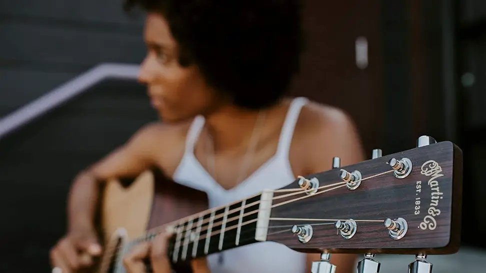 A woman playing her acoustic-electric guitar at a local coffee shop.