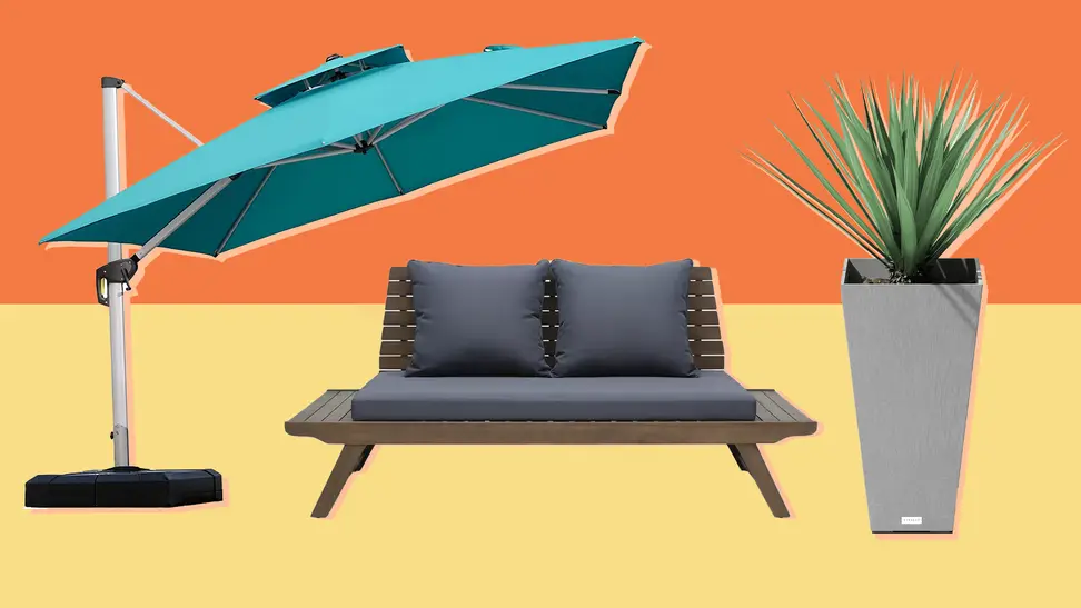 A large patio umbrella hangs over an outdoor sofa that sits next to an outdoor rectangular planter with a plant inside
