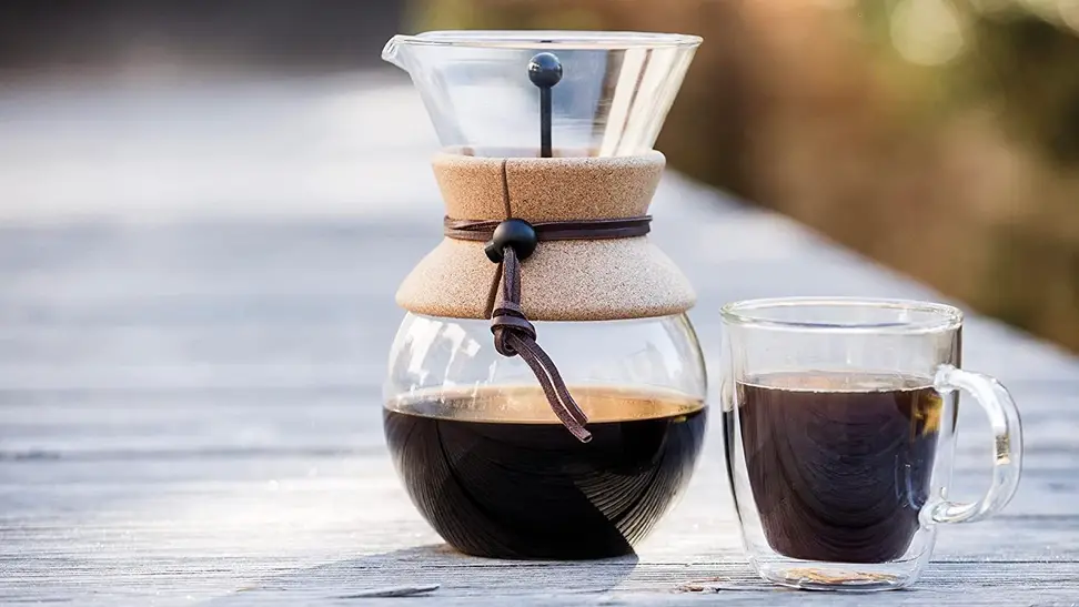 Clear coffee mugs being used by two friends to drink espresso on the porch.