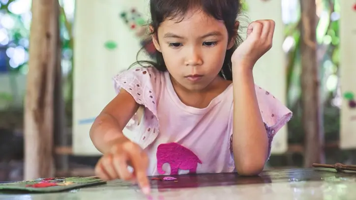 Child wearing pink shirt playing with stickers