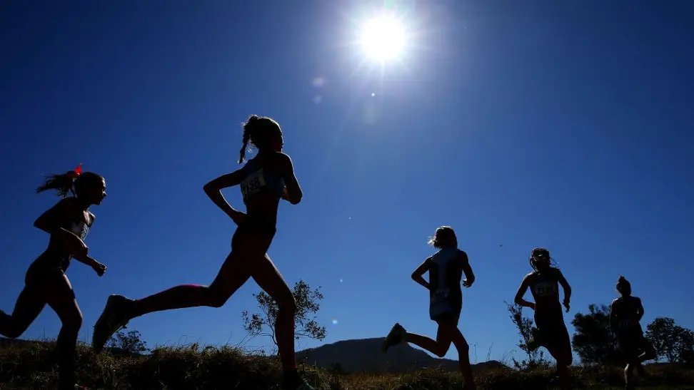 A parade of runners silhouetted against a brilliant blue sky