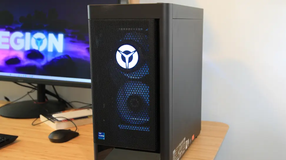 A black Lenovo desktop tower sits on a desk next to a computer monitor.