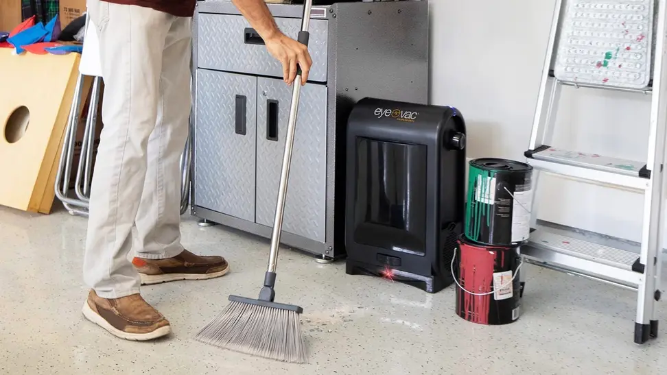 A man using his electric dustpan to clean his garage.