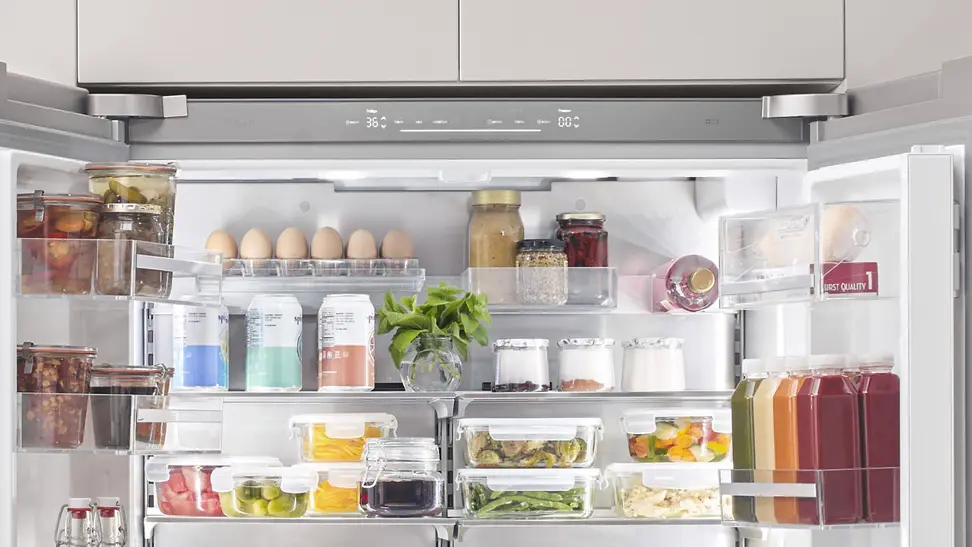 Open Bosch refrigerator showing lots of lovely food and beverages.