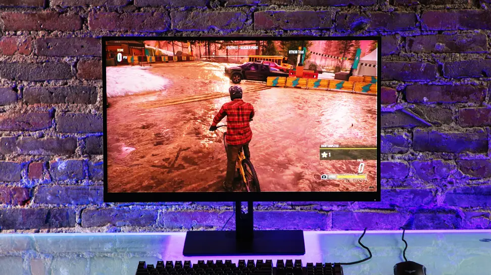 NZXT’s affordable, high-quality Canvas 27Q backlit by purple lighting in front of a brick wall.