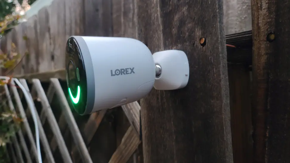 Lorex 4K Spotlight mounted on wooden fence outdoors.