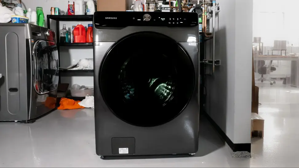 A black washing machine with a front-load door sits in a storage room