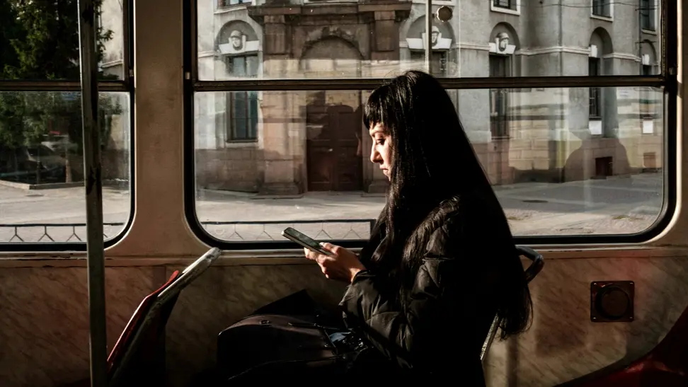 A passenger on public transit uses a smartphone.