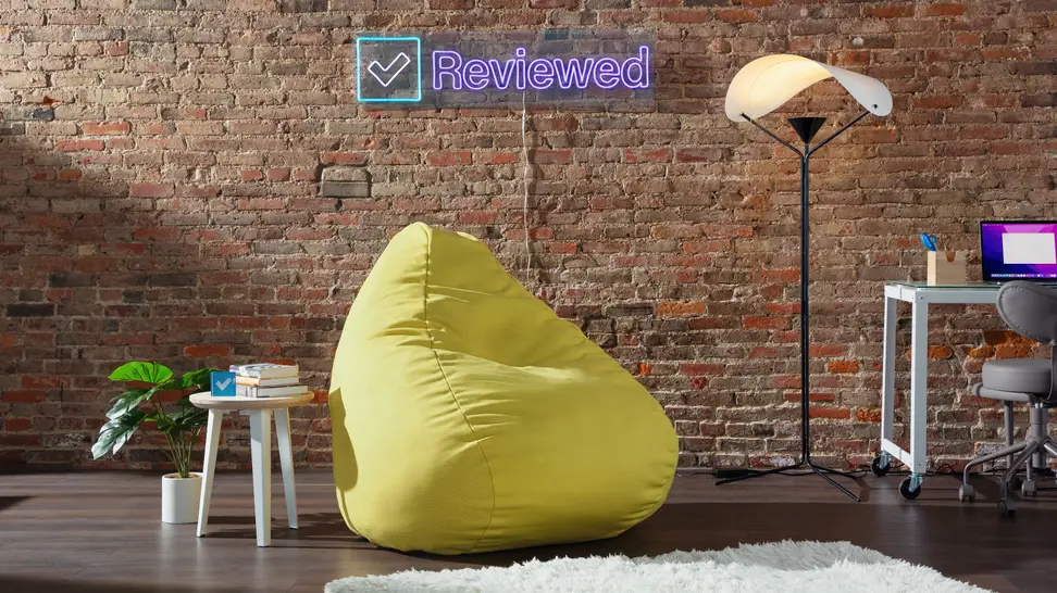 Yellow Floyd Squishy Chair in front of brick wall next to side table, and floor Y-Lamp.