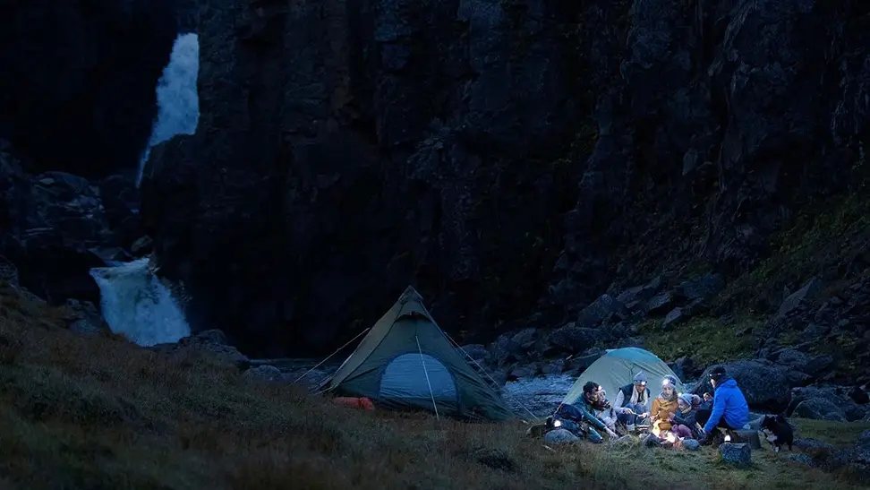 Campers hanging out and wearing headlamps.