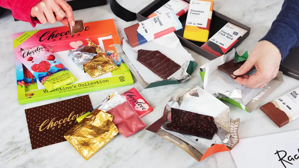 Two hands taking chocolate from a pile of various bars and wrappers