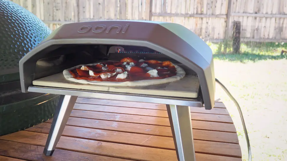 Close-up of a large, round pizza inside an Ooni outdoor pizza oven.