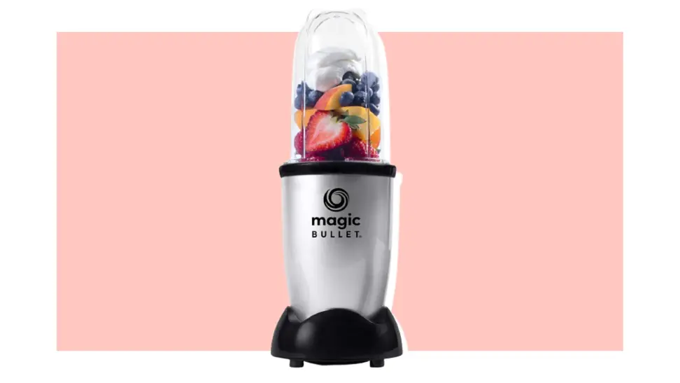 Magic Bullet blender filled with fruit on a pink background