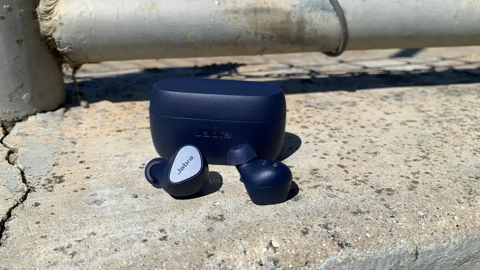 Jabra Elite 4 Earbuds outside of a black case on a rock.