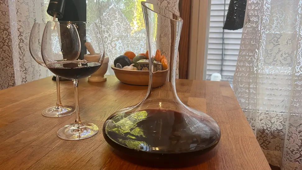 Red wine in a Le Chateau decanter next to a glass of wine.