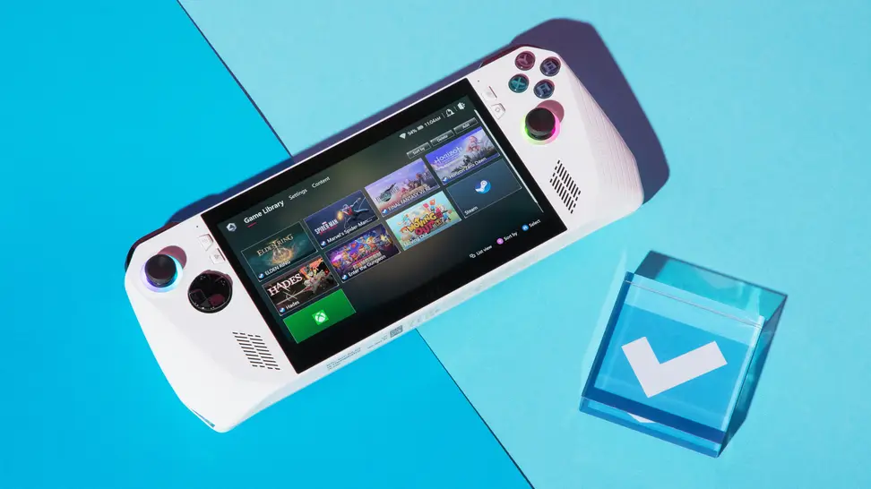 A white handheld gaming console surrounded by a steam deck and wireless controller