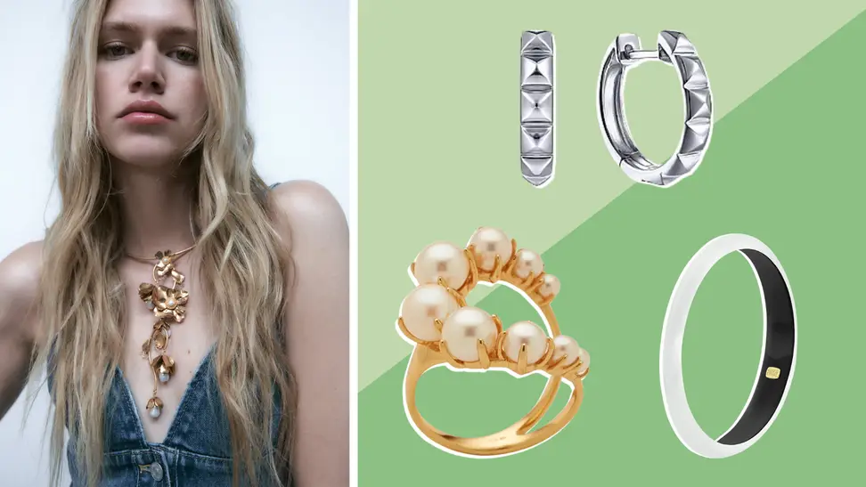 A woman wears a statement necklace, as well as a pair of studded silver hoop earrings, a gold and pearl ring, and a silver bracelet.
