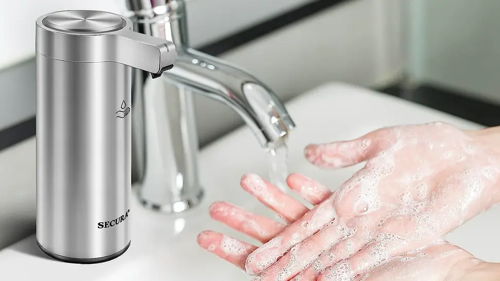 A pair of light-skinned hands are lathered with foamy soap under a running faucet. There is a Secura hand-soap dispenser in the foreground.