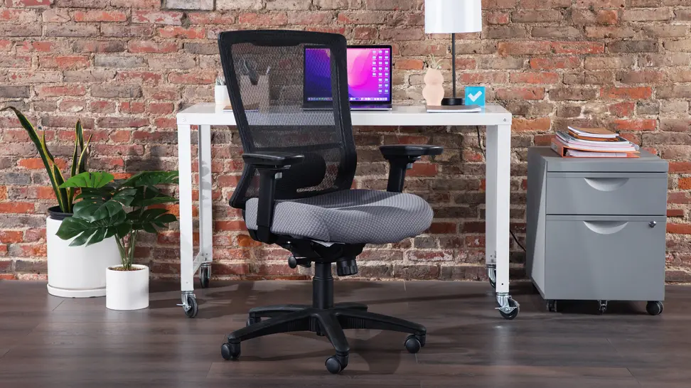Office chair in front of desk with laptop and small file cabinet indoors.