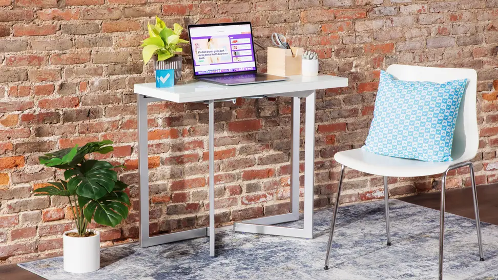 The Expand Furniture Mini Flip set up as a desk against a brick wall with an office chair