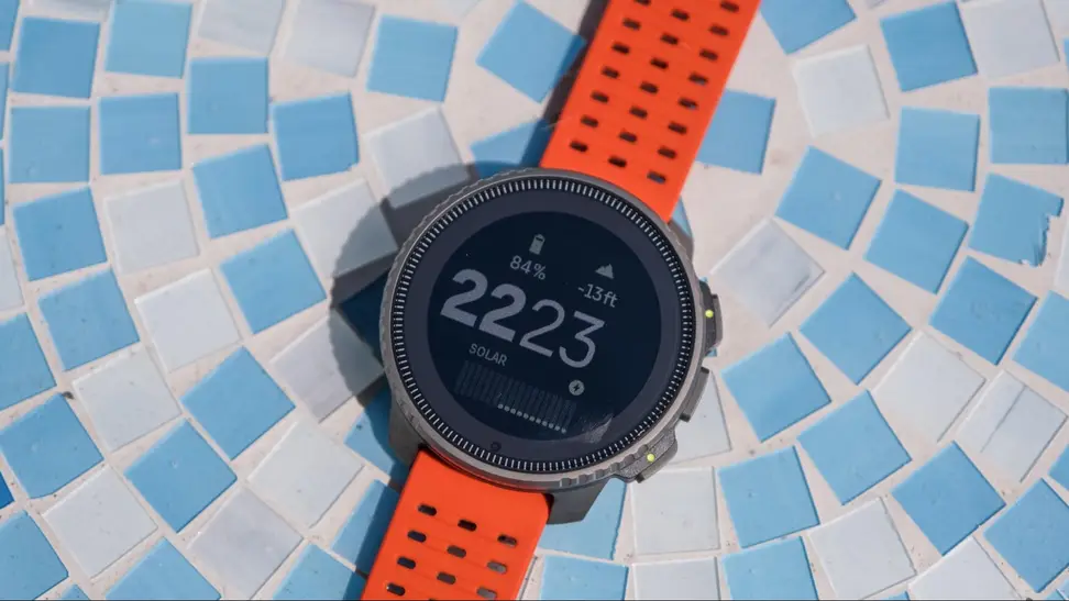 The Suunto Vertical Titanium Solar outdoor watch sits on a blue mosaic tabletop